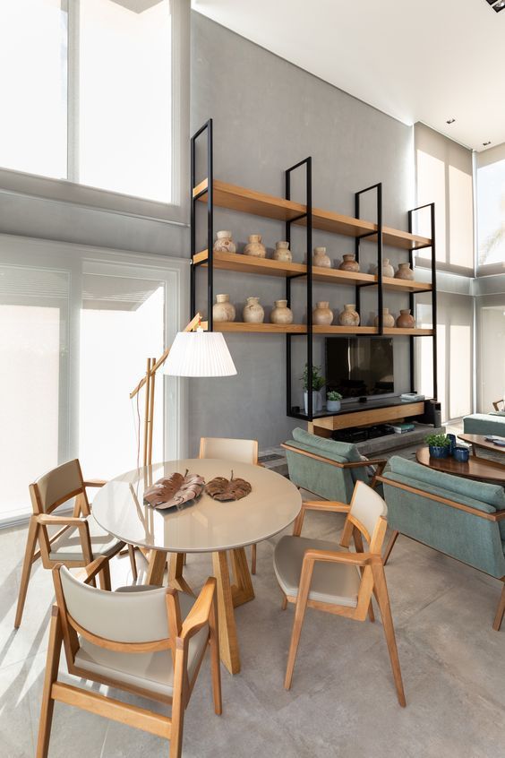 Uma sala de estar com mesa, cadeiras e estantes.
