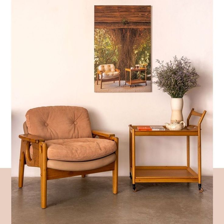 Uma cadeira e um carrinho estão em uma sala com um quadro na parede acima deles