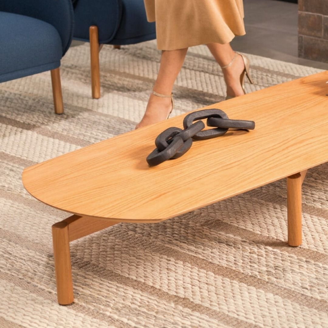 Uma mulher está ao lado de uma mesa de centro de madeira com uma corrente.