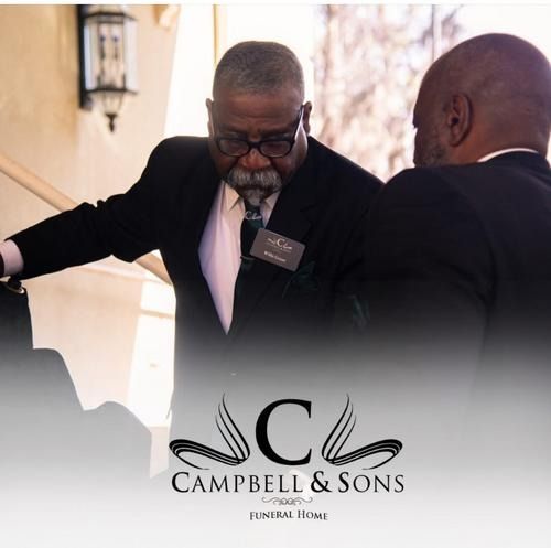 Two men in black suits talking at a formal event, with a Campbell & Sons Funeral Home logo below