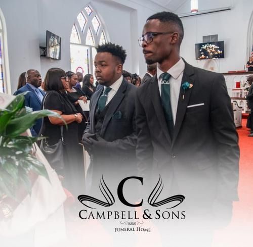Mourners in black suits stand in a church during a funeral service, with Campell & Sons Funeral Home logo below.