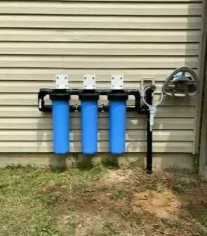 Three blue water filters are hanging on the side of a house. Three blue water filters are hanging on the side of a house.