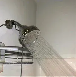 A shower head is spraying water in a bathroom.