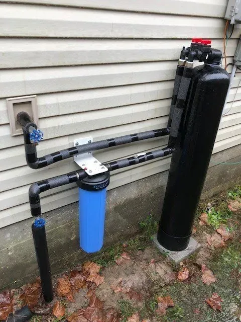 A water filter is attached to the side of a house.