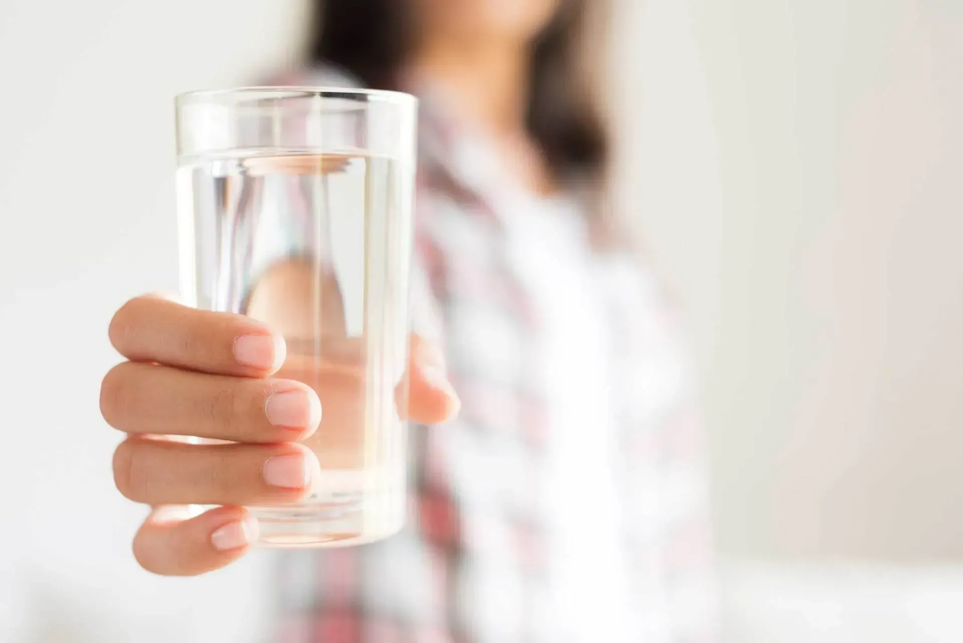 A woman is holding a glass of water in her hand.