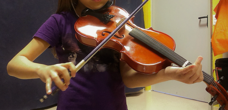 Ragazza che suona il violino, indossa un abito color ruggine, su uno sfondo verde tenue.