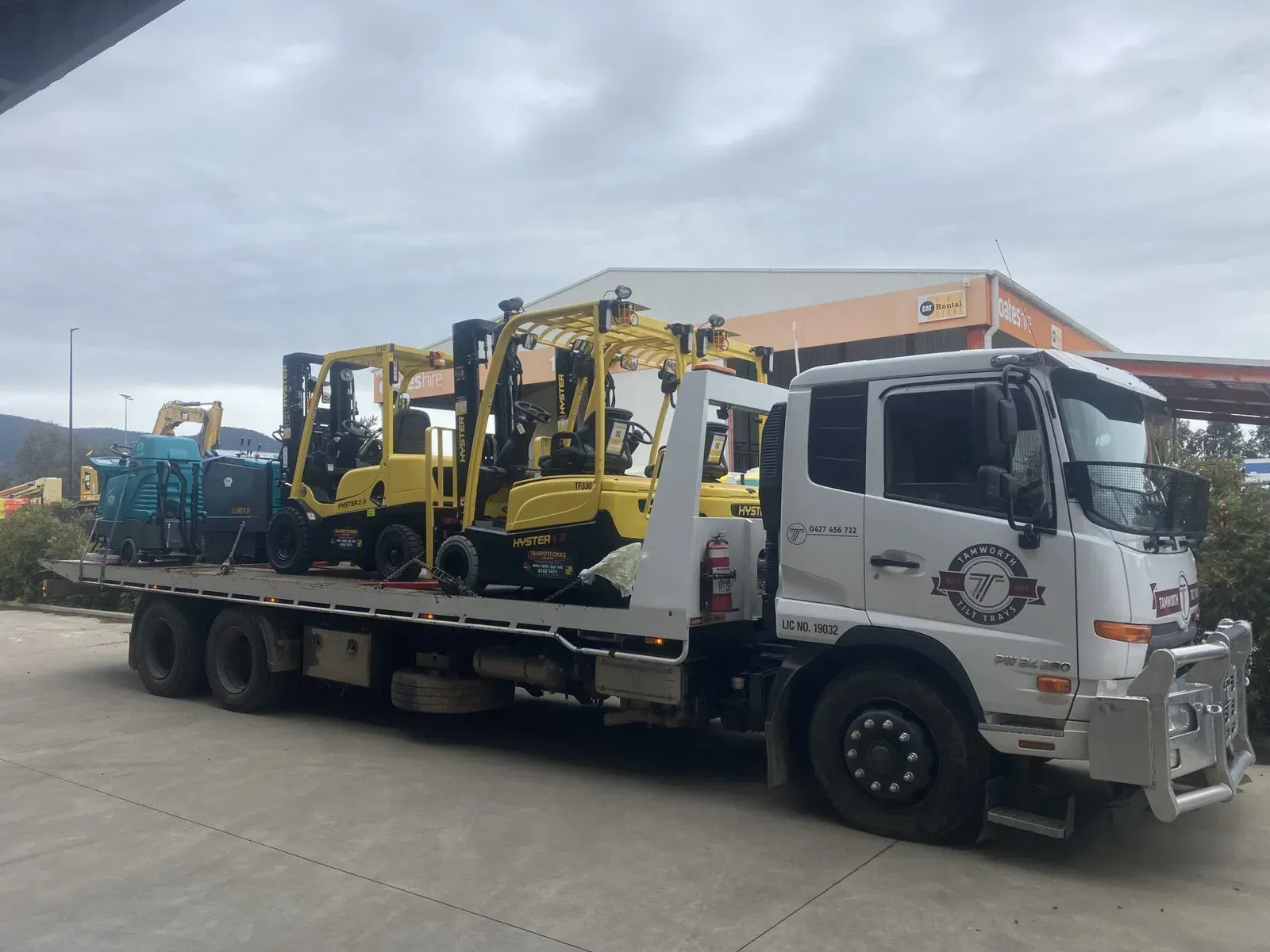 A Flatbed Truck Transporting Several Yellow Industrial Forklifts — Tamworth Tilt Trays in Tamworth, NSW