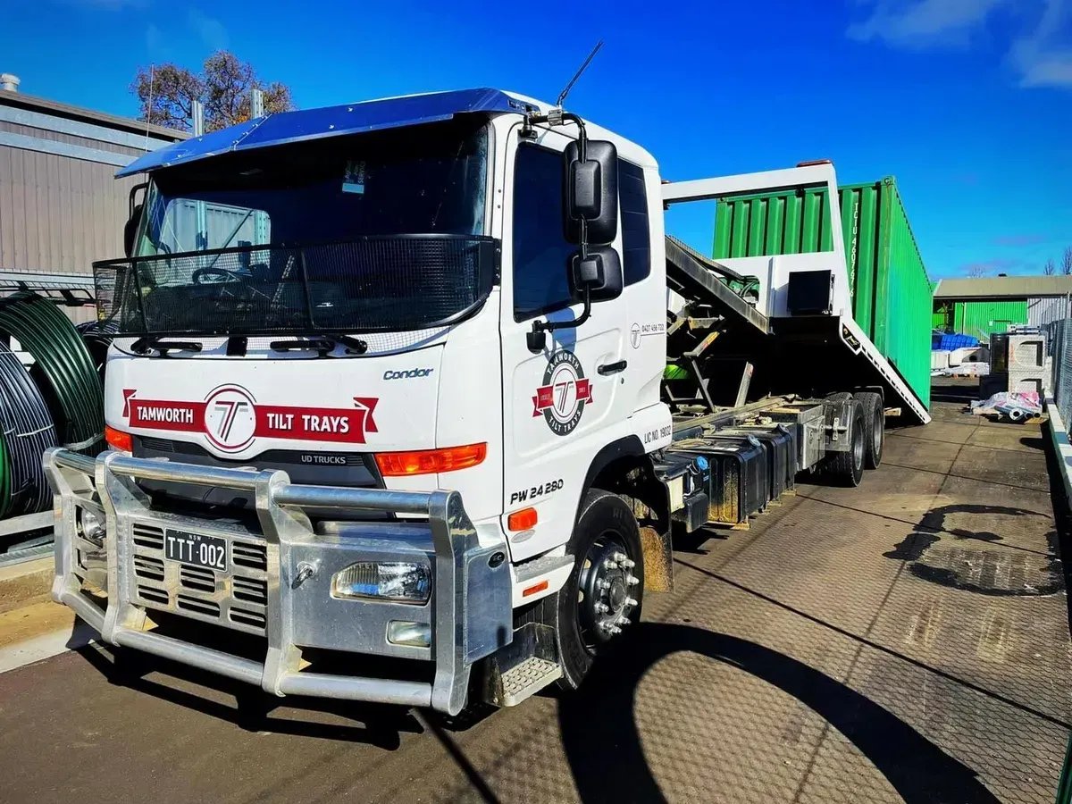 A White Hino Truck With a Green Container Parked on a Paved Lot — Tamworth Tilt Trays in Tamworth, NSW