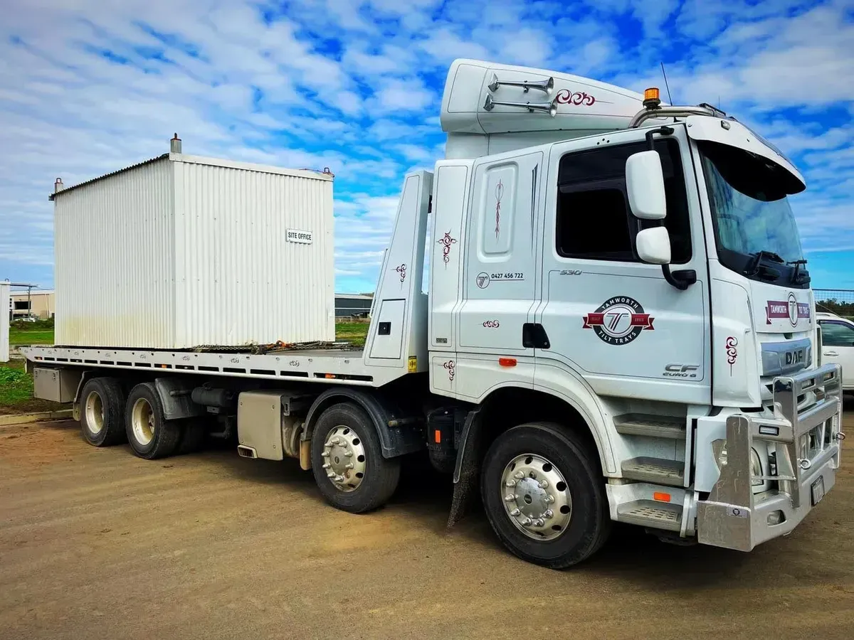 A White Flatbed Truck Carrying a Small White Shipping Container — Tamworth Tilt Trays in Tamworth, NSW