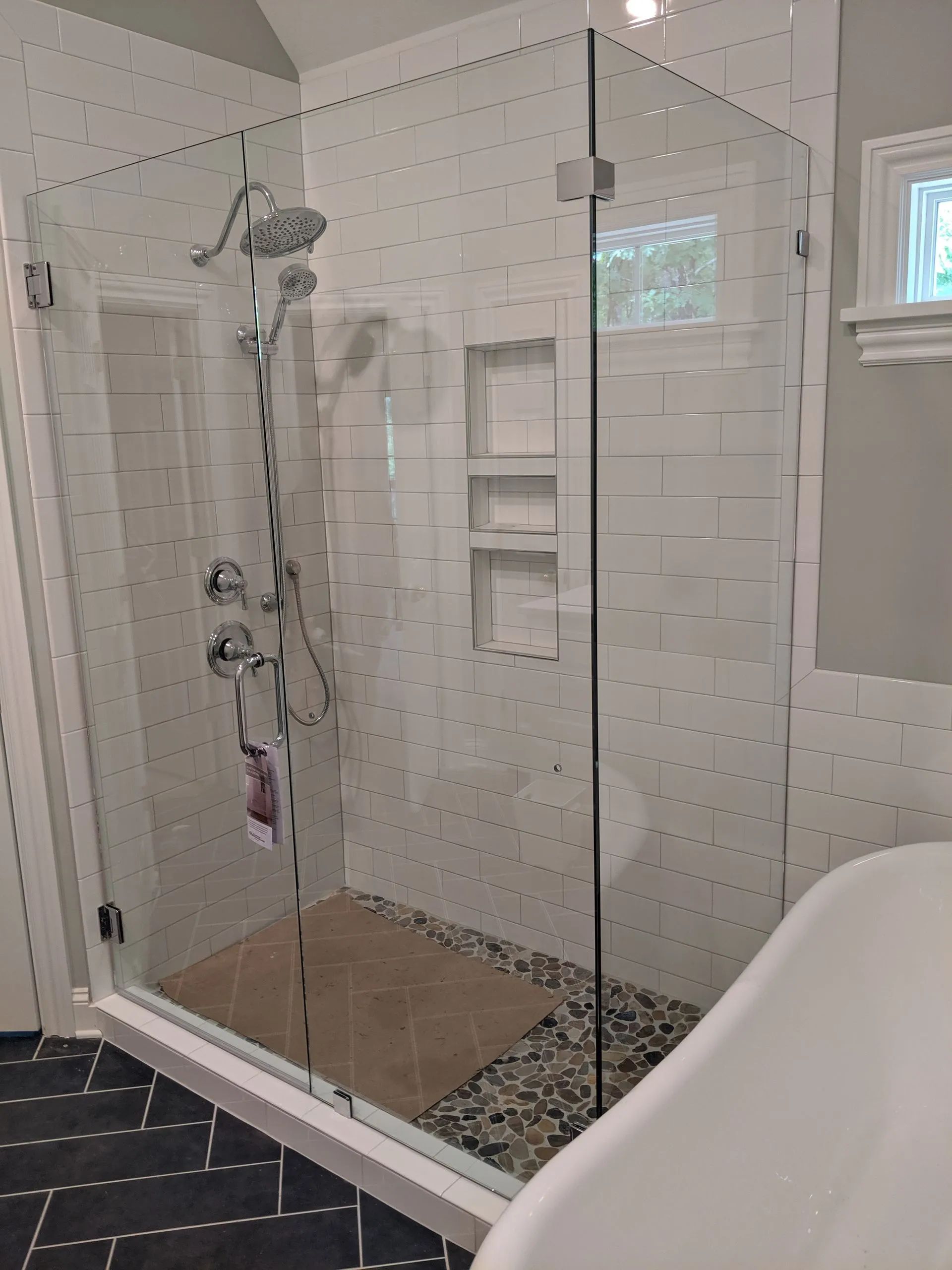 Glass walk-in shower with white subway tiles, built-in niche, and dark floor tile