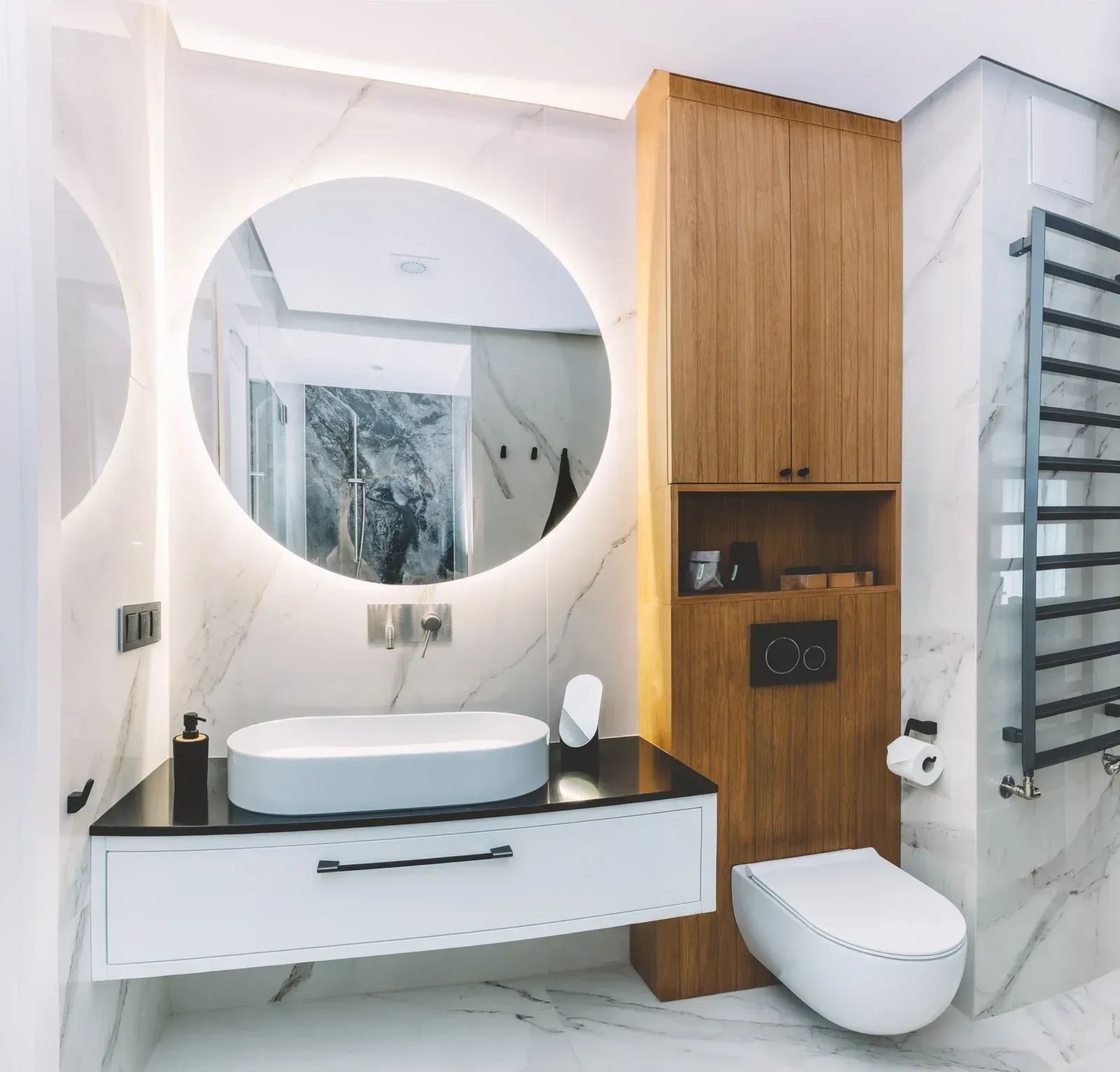 Modern bathroom with round backlit mirror, floating vanity, toilet, and wood cabinet