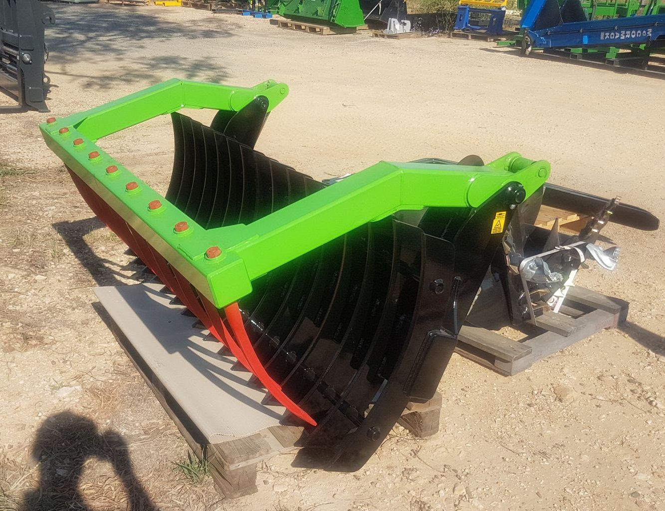 A green and black machine is sitting on a pallet in the dirt.