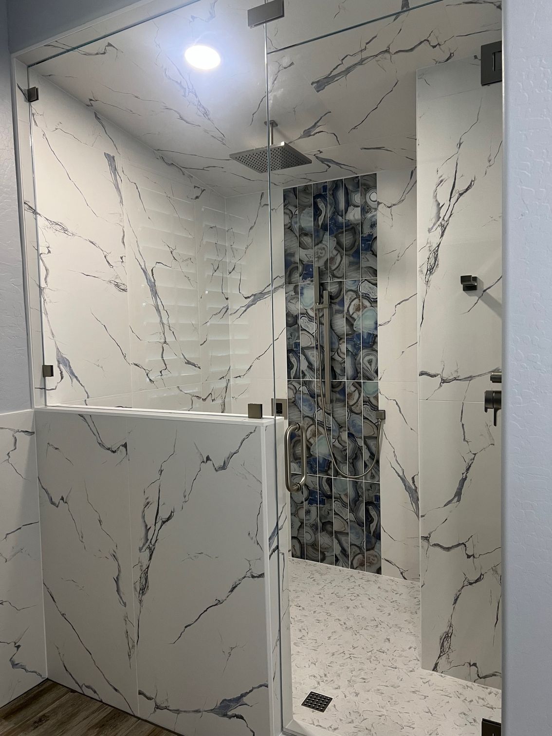 Modern bathroom with marble-pattern walls, black rain shower fixtures, steam generator, and a tiled ceiling