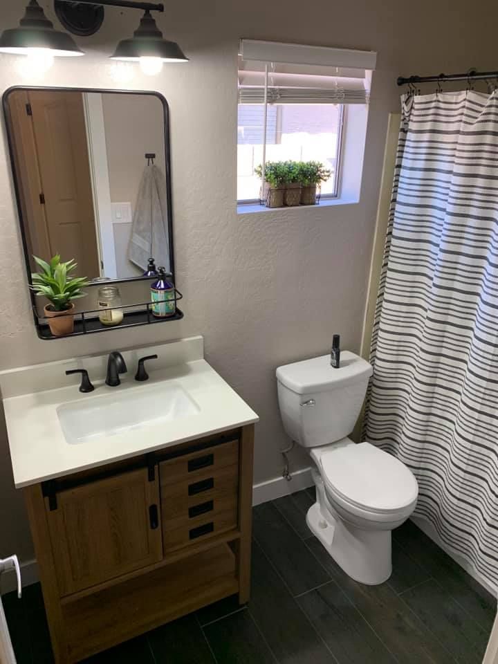 Small bathroom with vanity, toilet, window, and striped shower curtain.