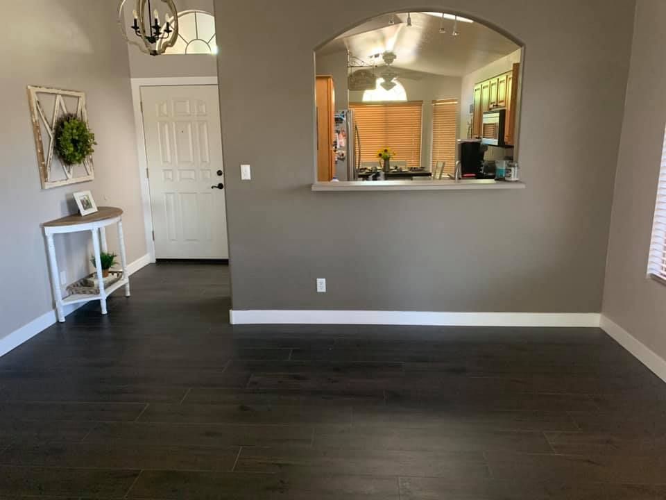 Empty living room with dark wood floors, gray walls, and a pass-through opening to the kitchen.