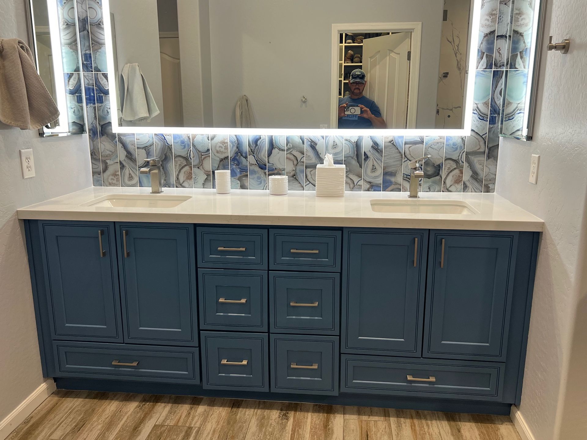 Blue bathroom vanity with lighted mirror, tile feature wall, refinished cabinets