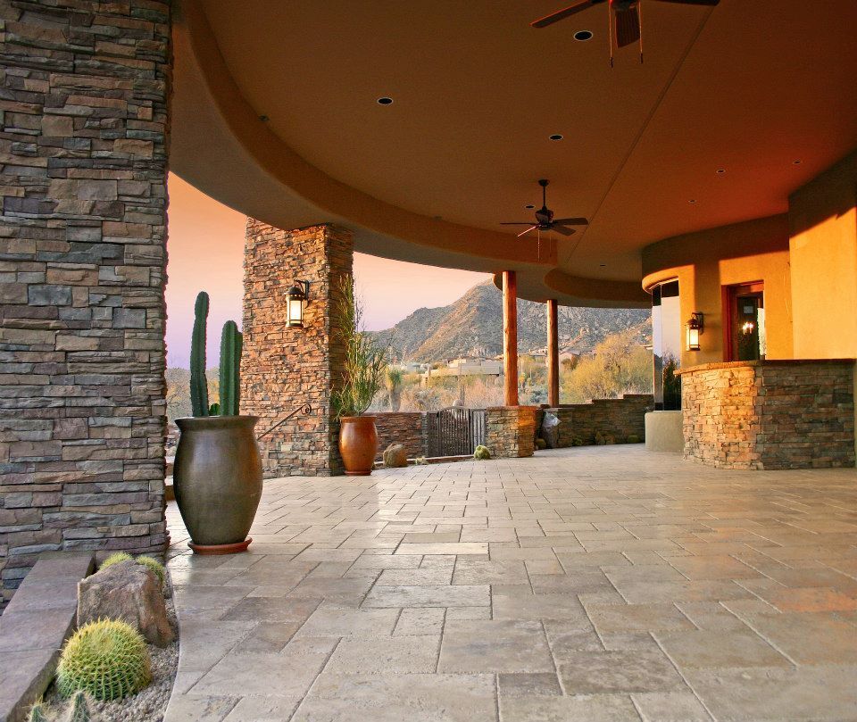 Covered stone patio with tiled floor, large clay pots, and mountain view at sunset