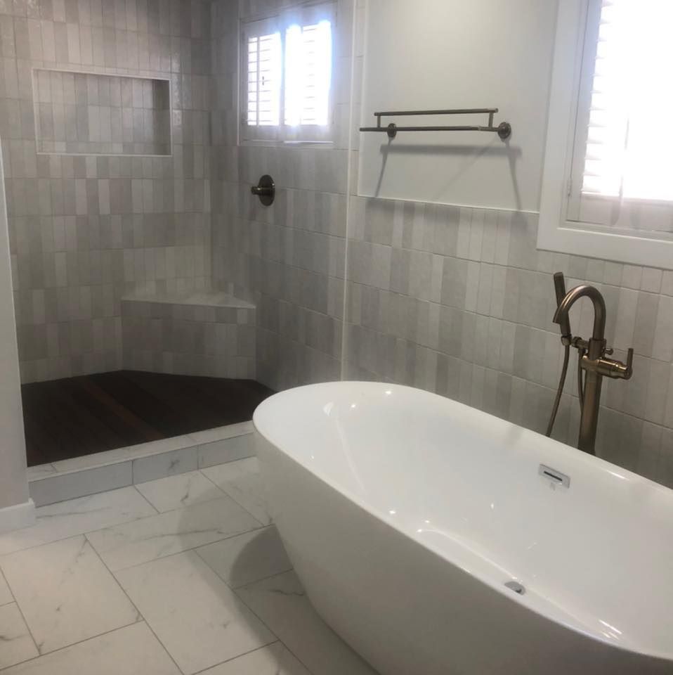 Modern bathroom with freestanding tub, tiled shower, and windows letting in natural light