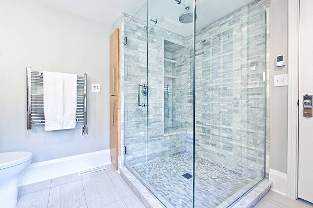 Modern bathroom with glass-enclosed shower, white tile, bathtub, and towel rack