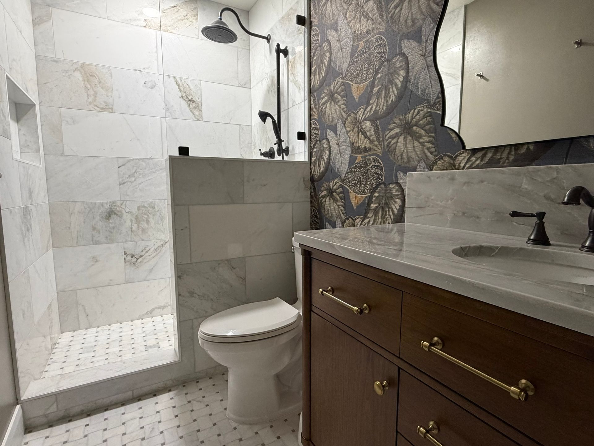 Small bathroom with walk-in shower, toilet, and dark wood vanity with marble countertop.
