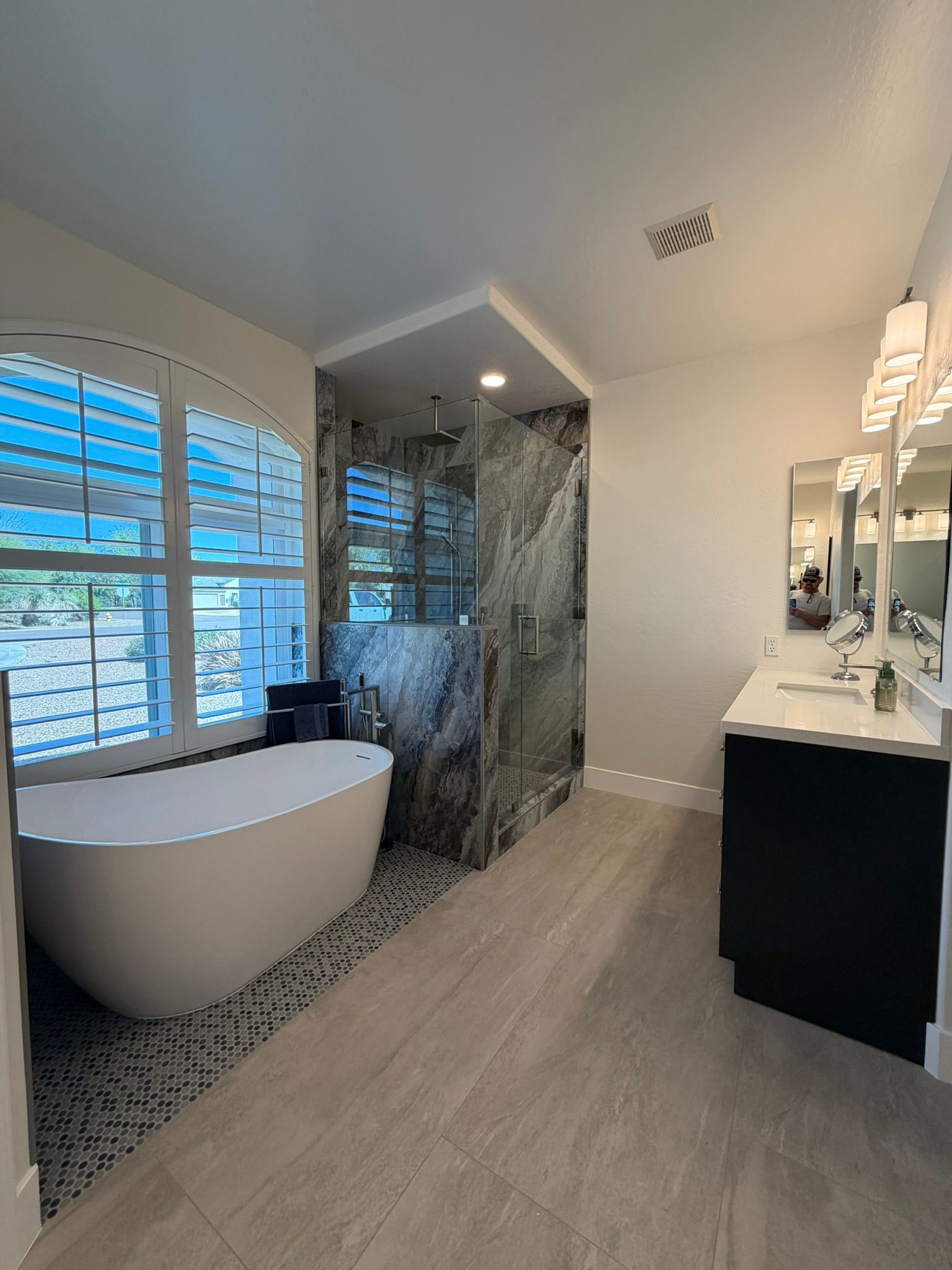 Modern bathroom with freestanding tub, marble shower, double vanity, and large windows