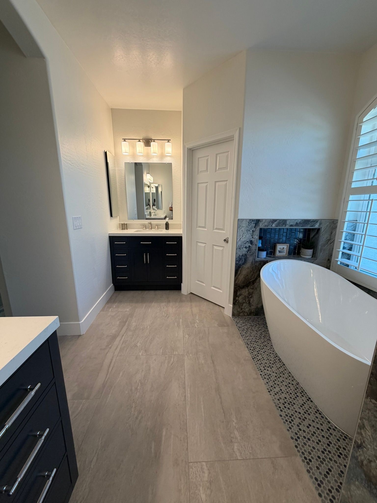 Modern bathroom with double vanity, white tub, and tiled walk-in shower.