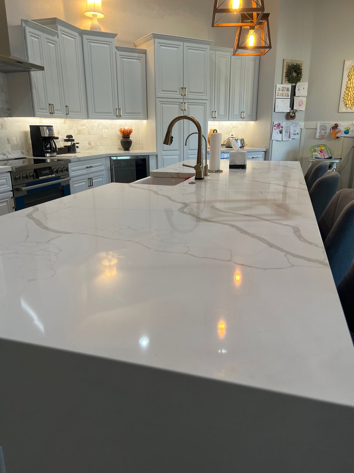 Bright modern kitchen with white cabinets, marble island, and pendant lights