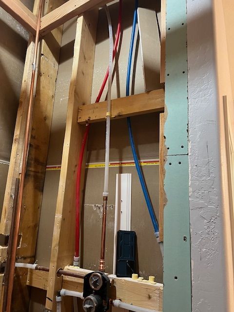 Unfinished interior wall framing with exposed studs and re-routing plumbing water lines 