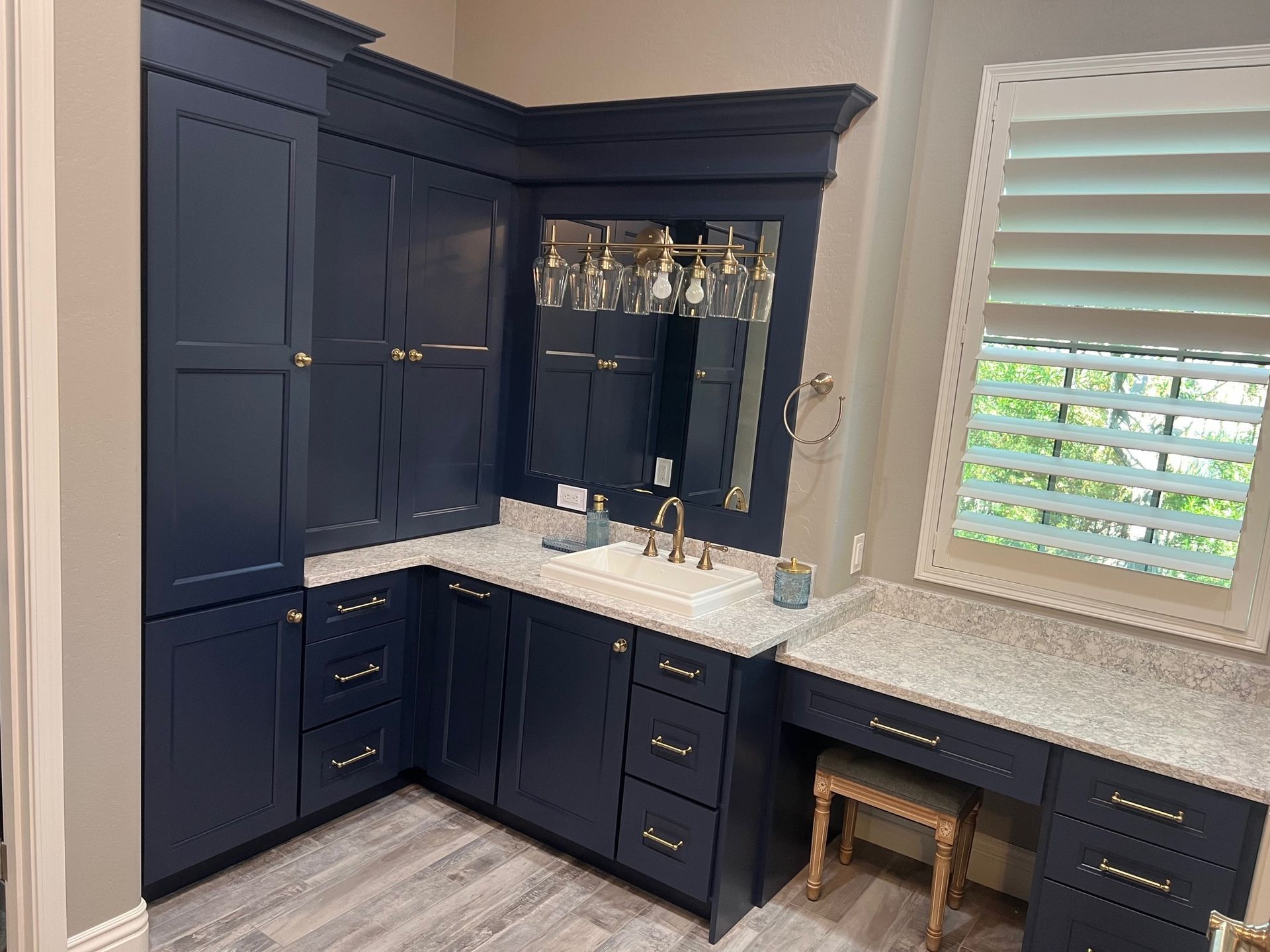 Navy blue built-in home bar with white countertop, mirrored shelves, and patterned backsplash.