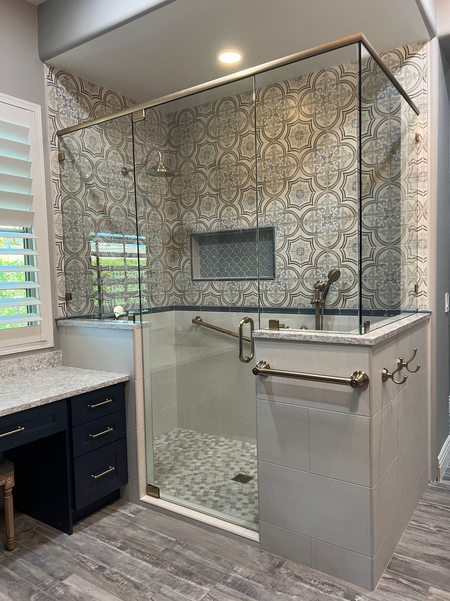 Modern bathroom with glass-enclosed shower, gray tile walls, and vanity with white countertop.