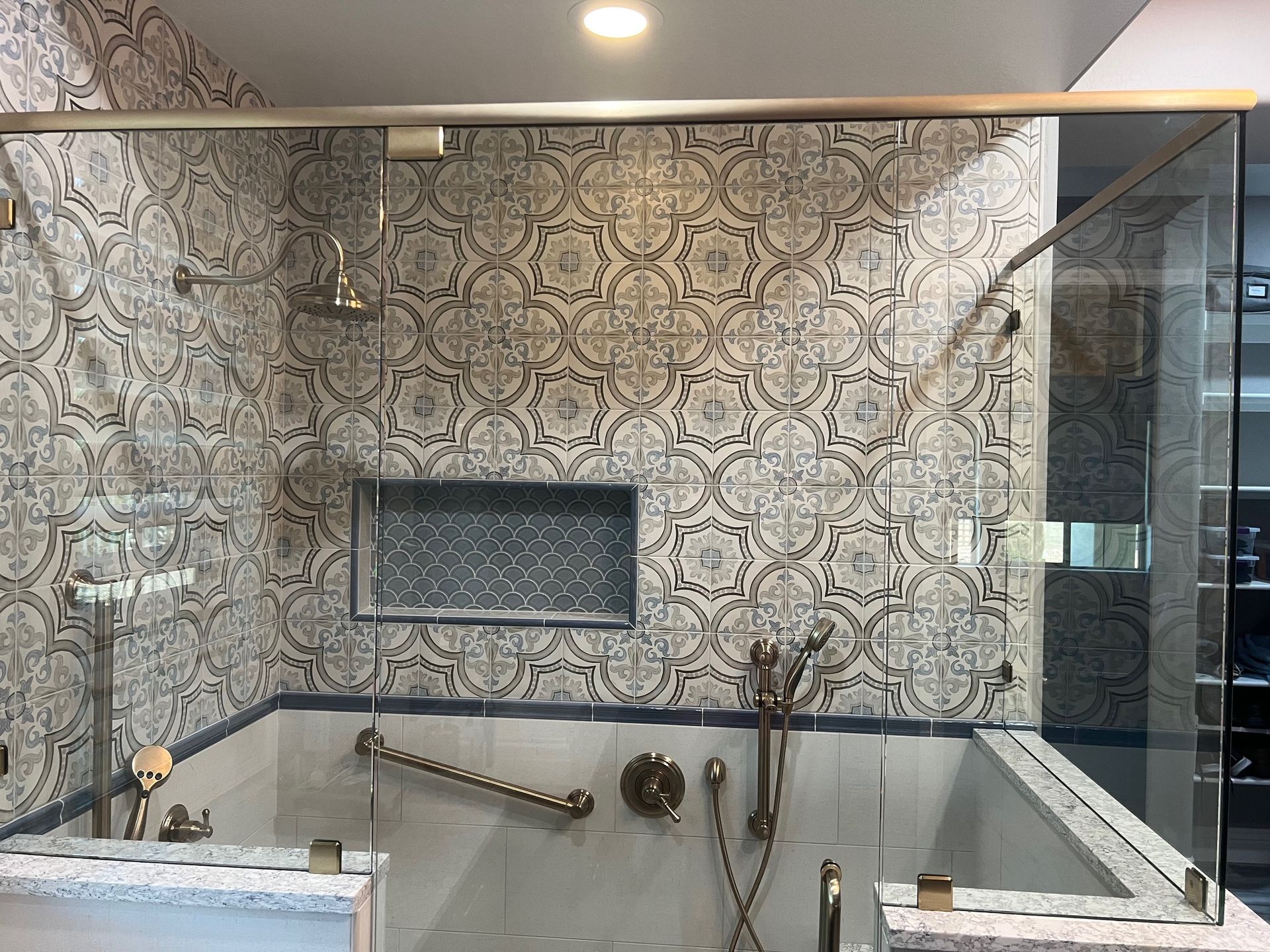 Patterned-tile bathroom with a bathtub, chrome fixtures, and a glass shower enclosure