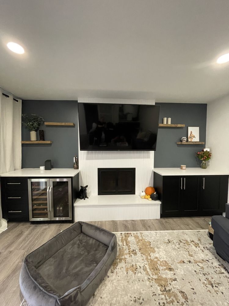Modern living room with fireplace, large TV, black cabinets, and gray pet bed on the floor