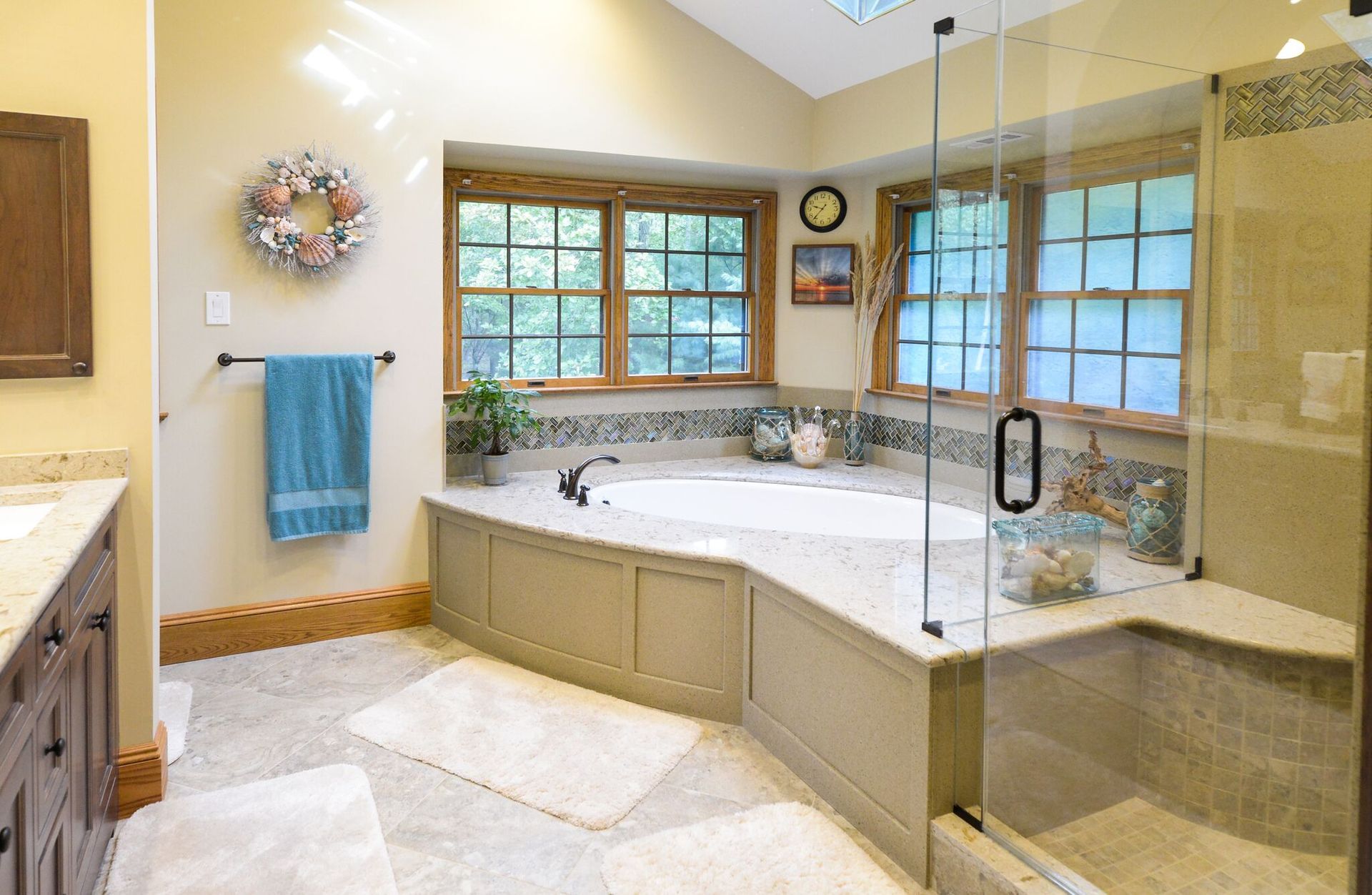 Bright bathroom with a built-in soaking tub, glass shower, and tan tile walls.