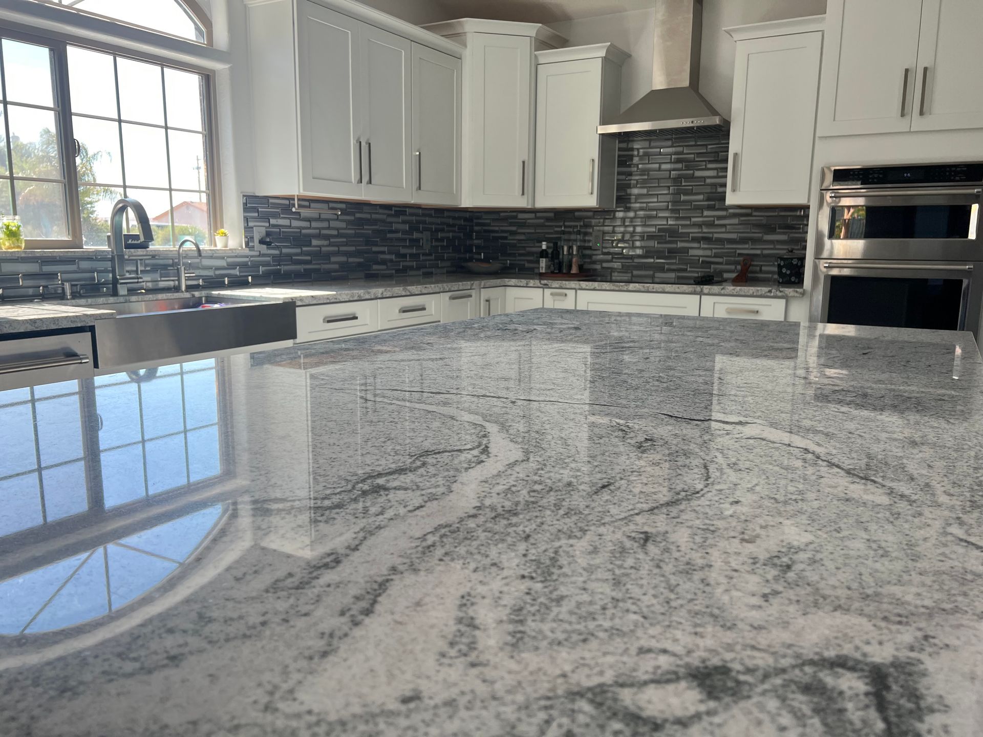 Bright kitchen with a polished gray-and-white granite countertop and white cabinets