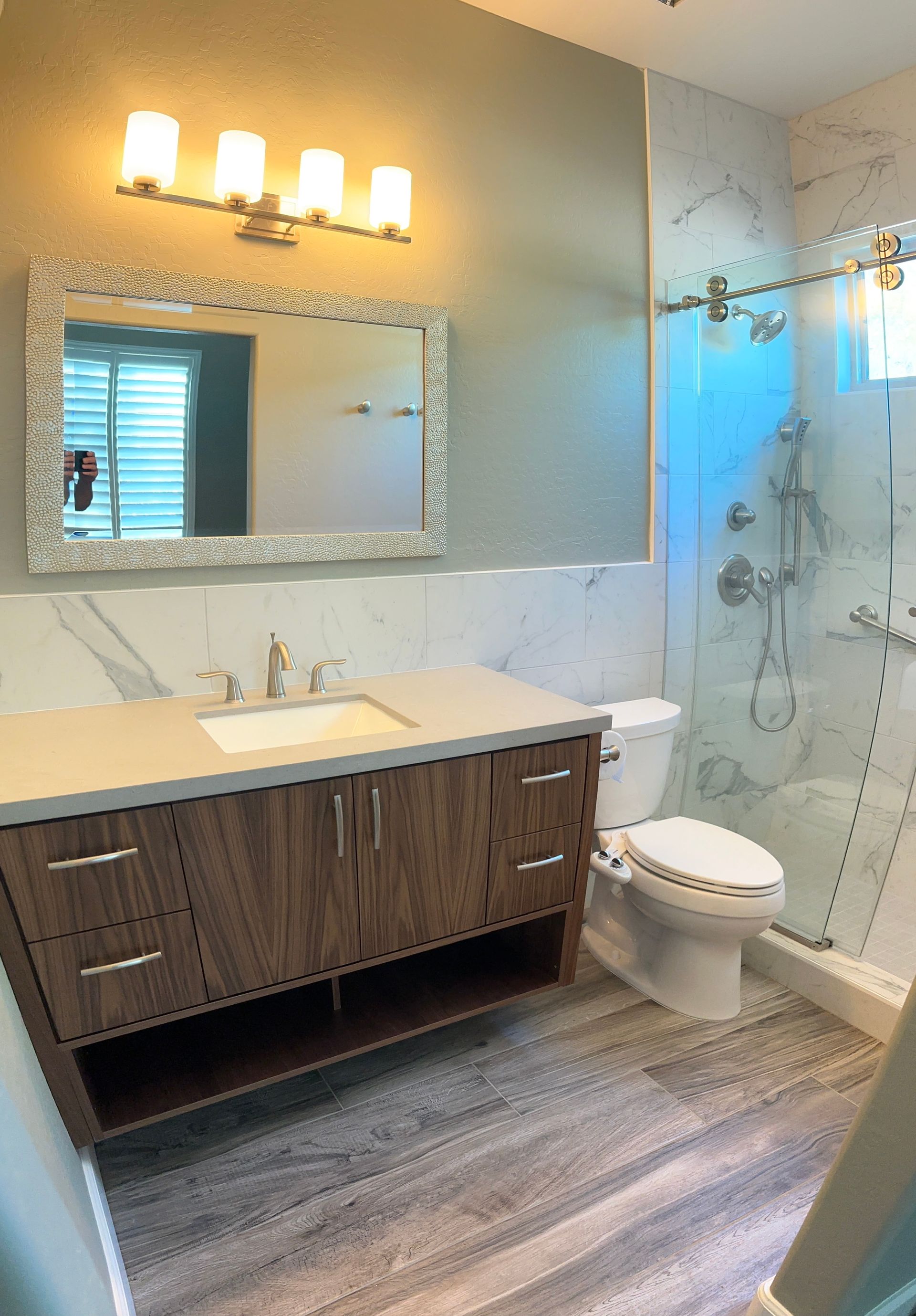Modern bathroom with vanity, lit mirror, toilet, and glass shower enclosure