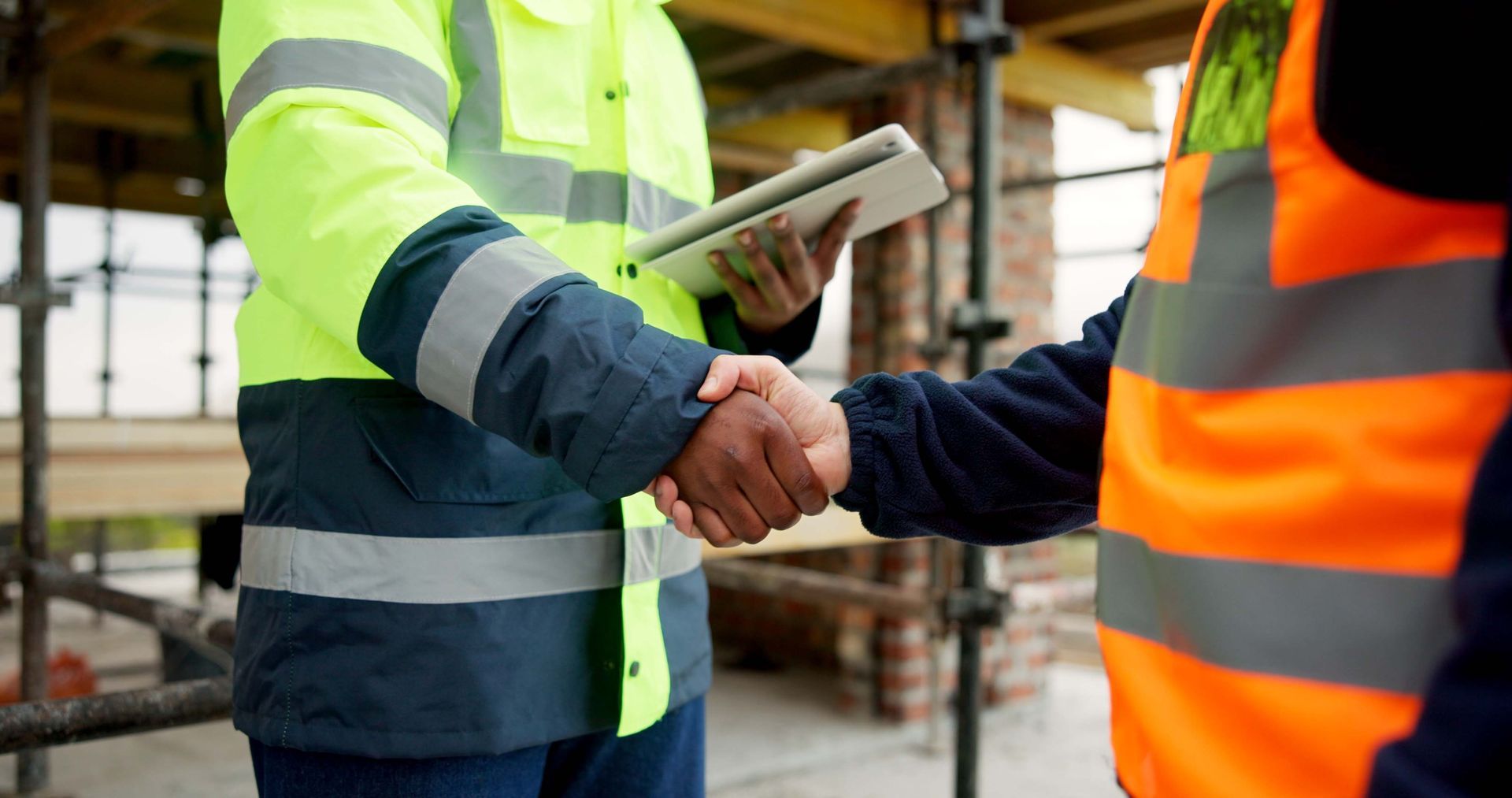 Men shaking hands on a construction site for an agreement.