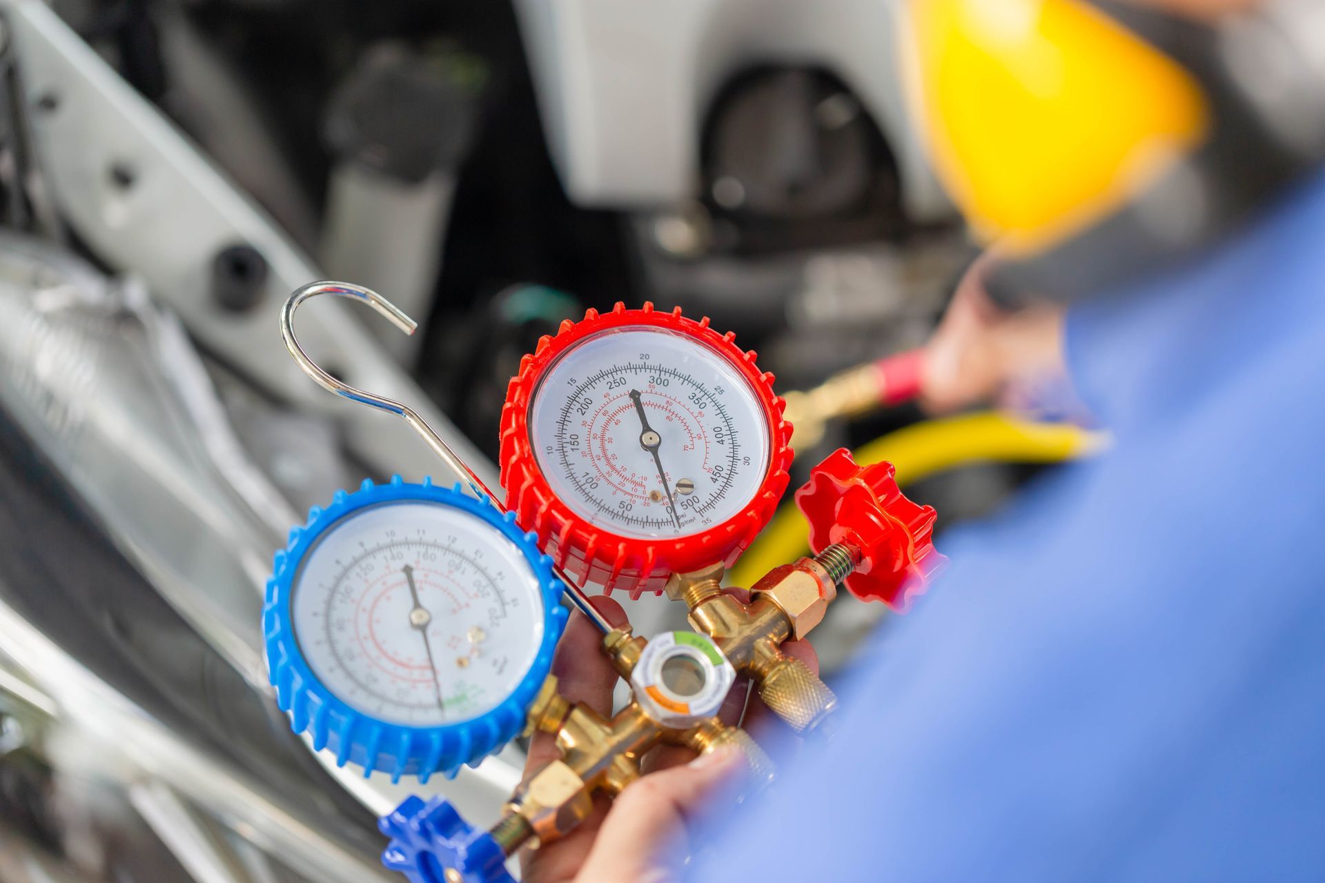 Blue and red pressure gauges being used to service car air conditioning system