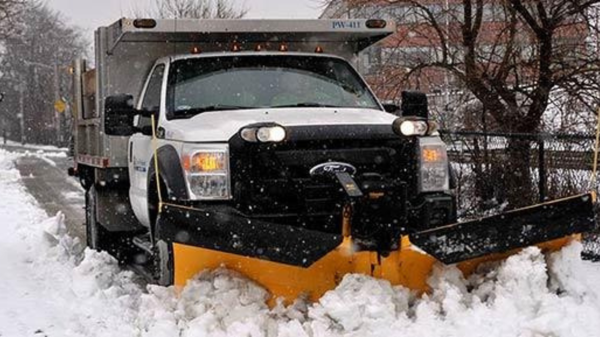 Snowplow truck pushing snow on a snowy road during a winter storm