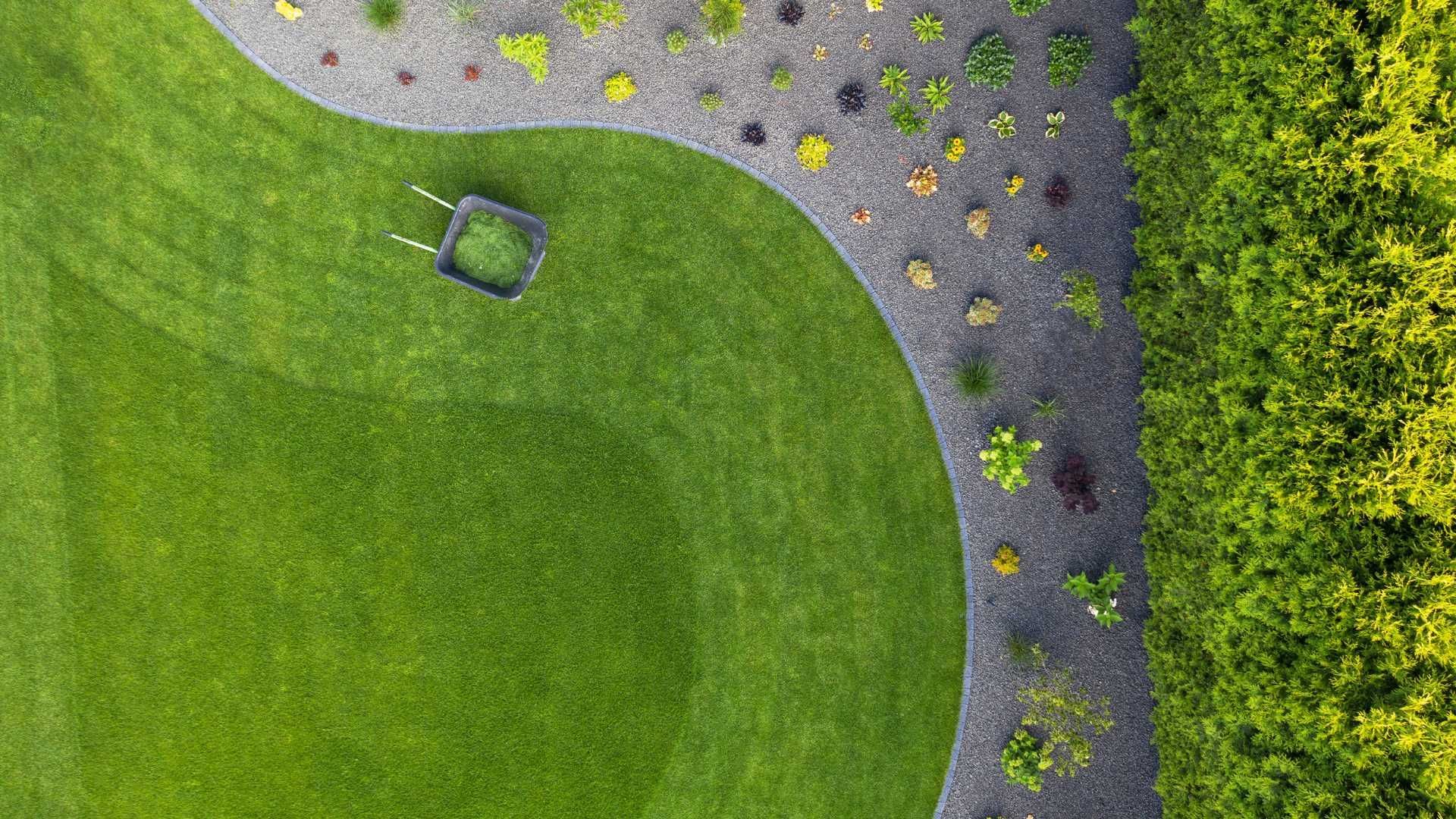 An aerial view of a lawn mower cutting a lush green lawn.