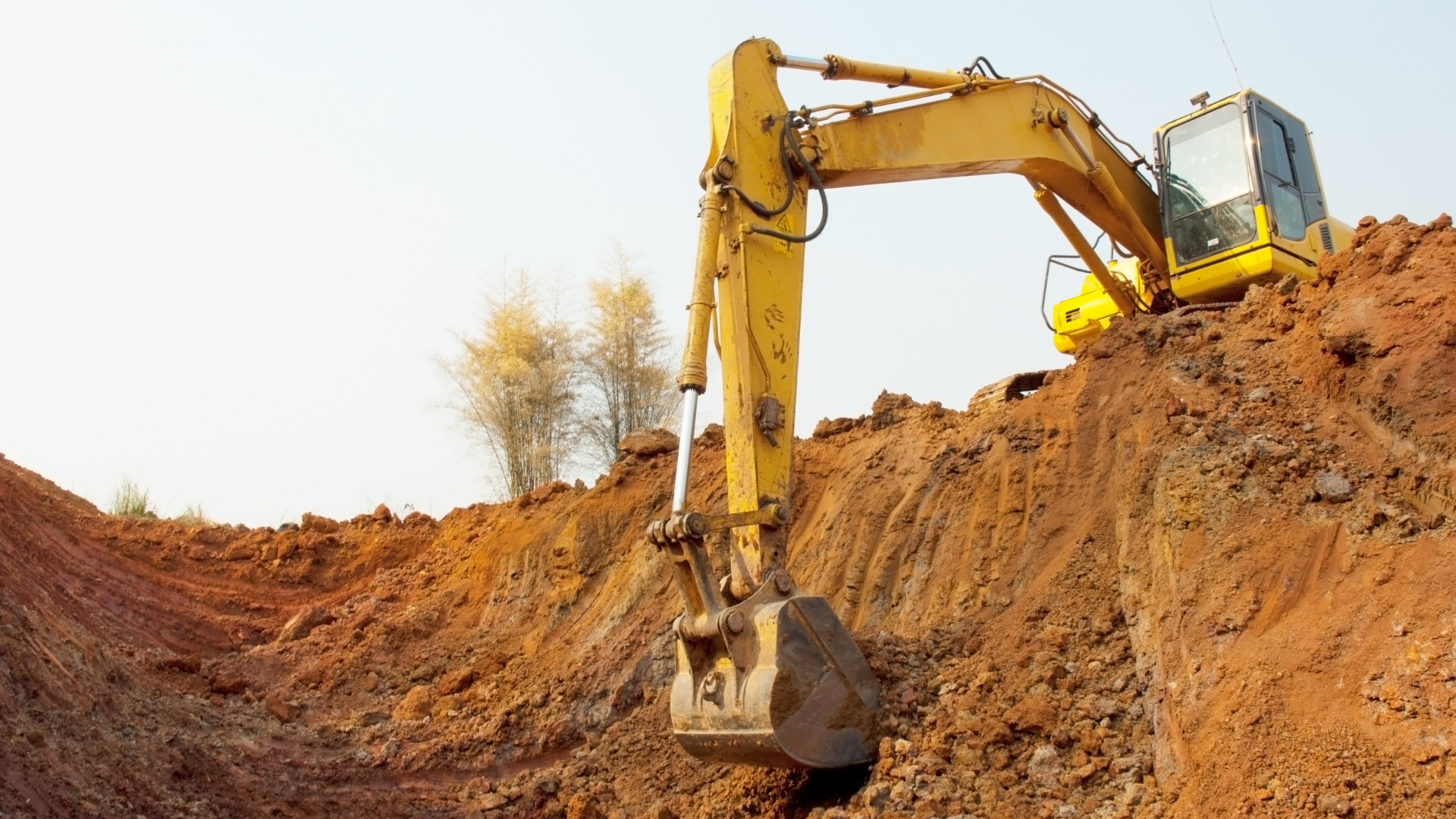 A yellow excavator is digging a hole in the dirt.