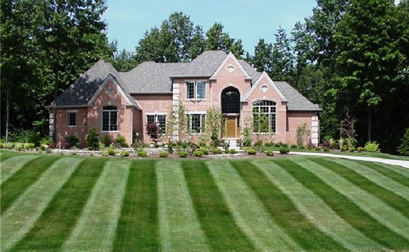 A large brick house with a lush green lawn in front of it