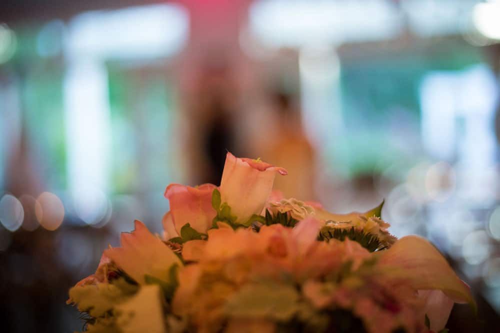 Close-up of a bouquet of soft pink and orange roses, blurred background with bokeh lights.