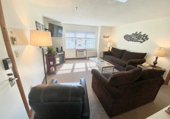 Living room with brown furniture, light beige walls, and a window.