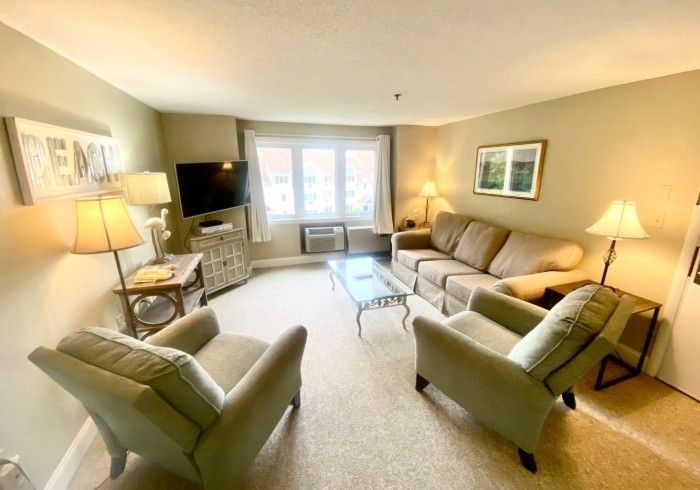 Living room with beige furniture, TV, and large window.