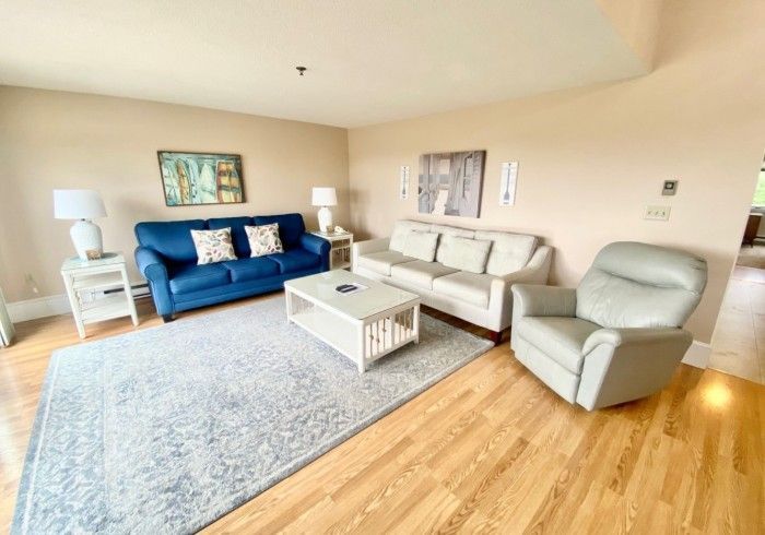 Living room with blue and beige sofas, white furniture, area rug, and recliner.