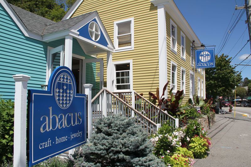 Abacus craft and home goods store, blue and yellow building with blue sign and floral landscaping.