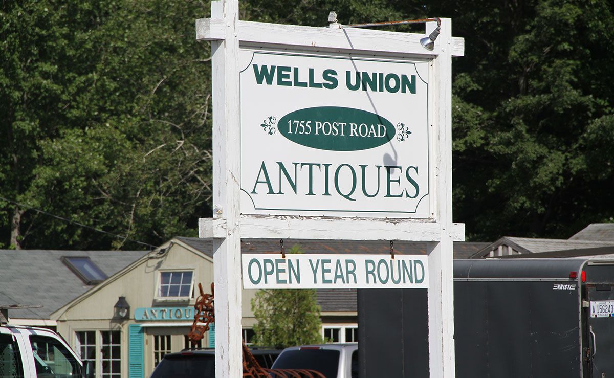Sign for Wells Union Antiques, white with green text, 