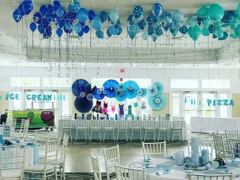 Blue and white decorated party room with balloons, tables, and decorations, with