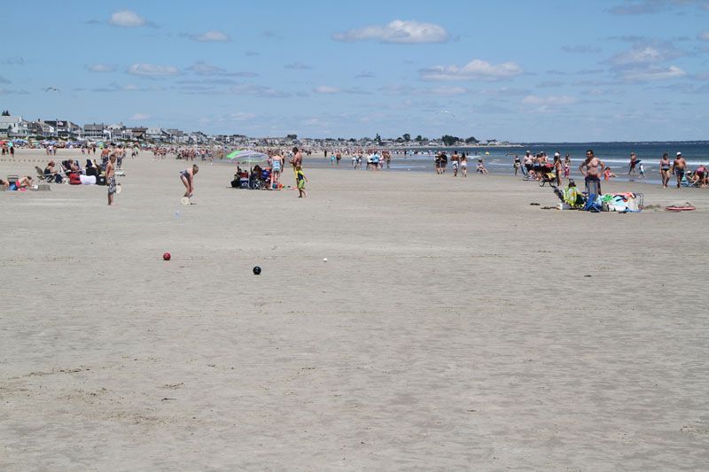 Beach scene with many people enjoying a sunny day.