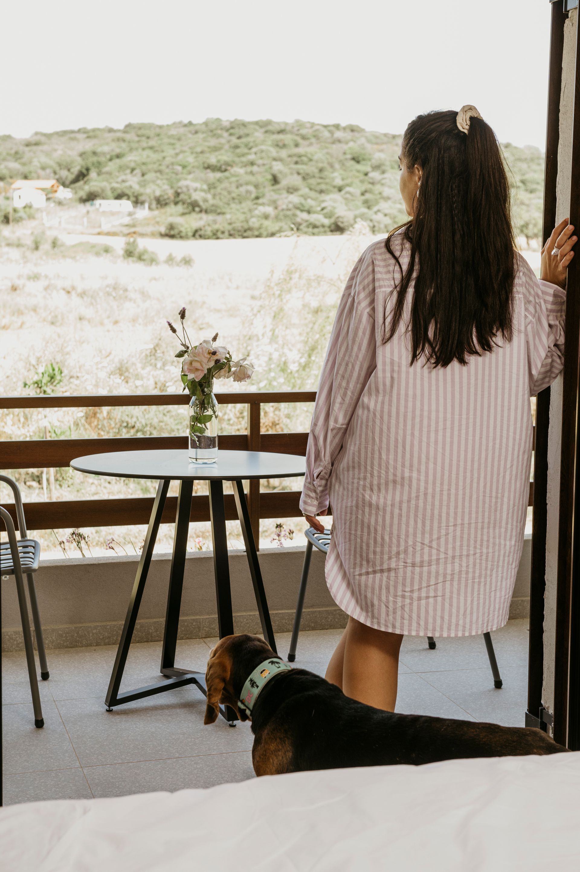 A woman is standing on a balcony with a dog.